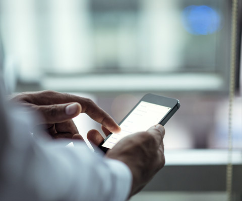 Man wearing white dress shirt using a black smart phone