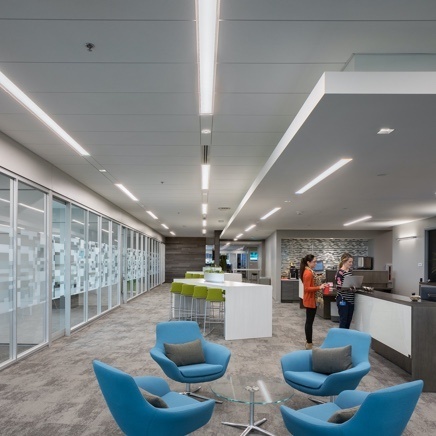 Open office setting with blue and brown couches and ceiling lighting