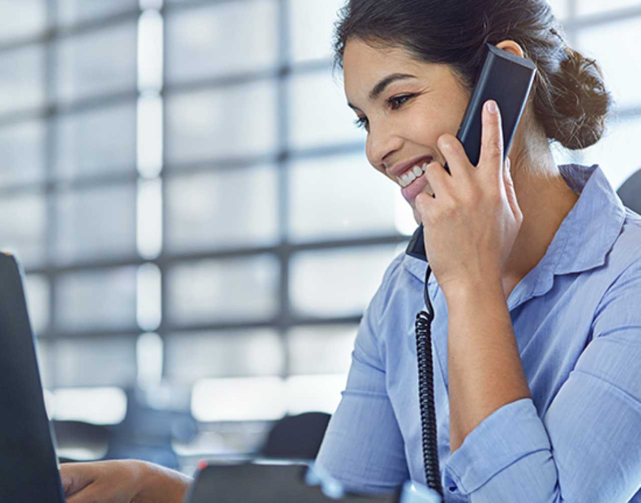 Woman talking on a phone while looking at a laptop