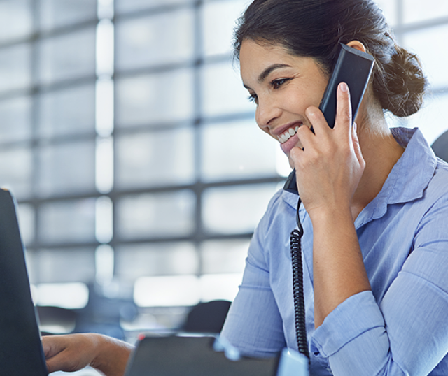 Woman speaking on phone while looking at computer